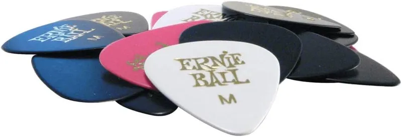 Ernie Ball medium gauge picks in assorted colors scattered in a pile, one of the best guitar picks for beginners.